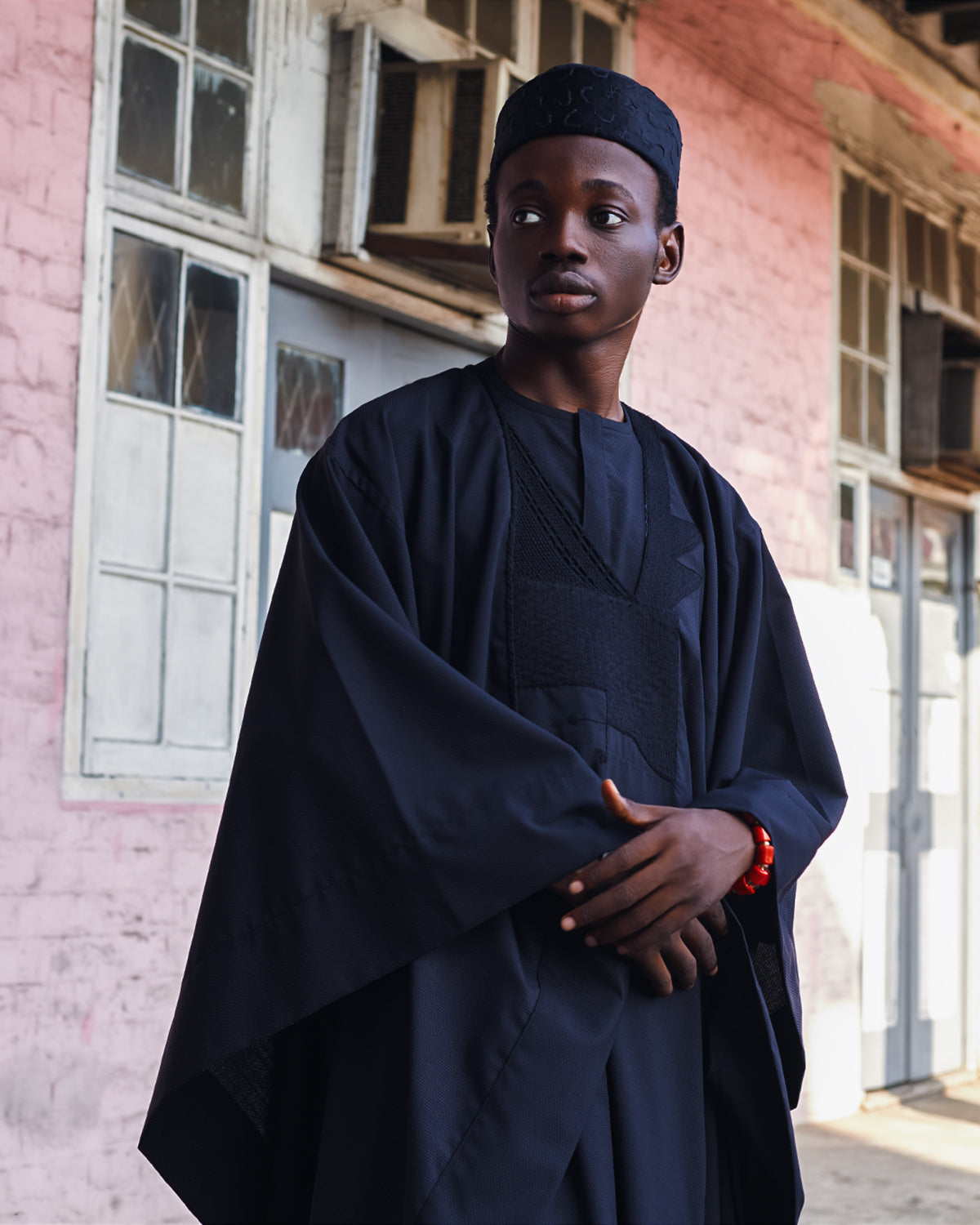 A man wearing black Agbada with a matching cap