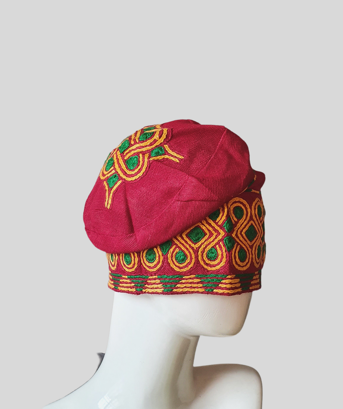 Red aso oke with green and yellow handknit embroidery cap