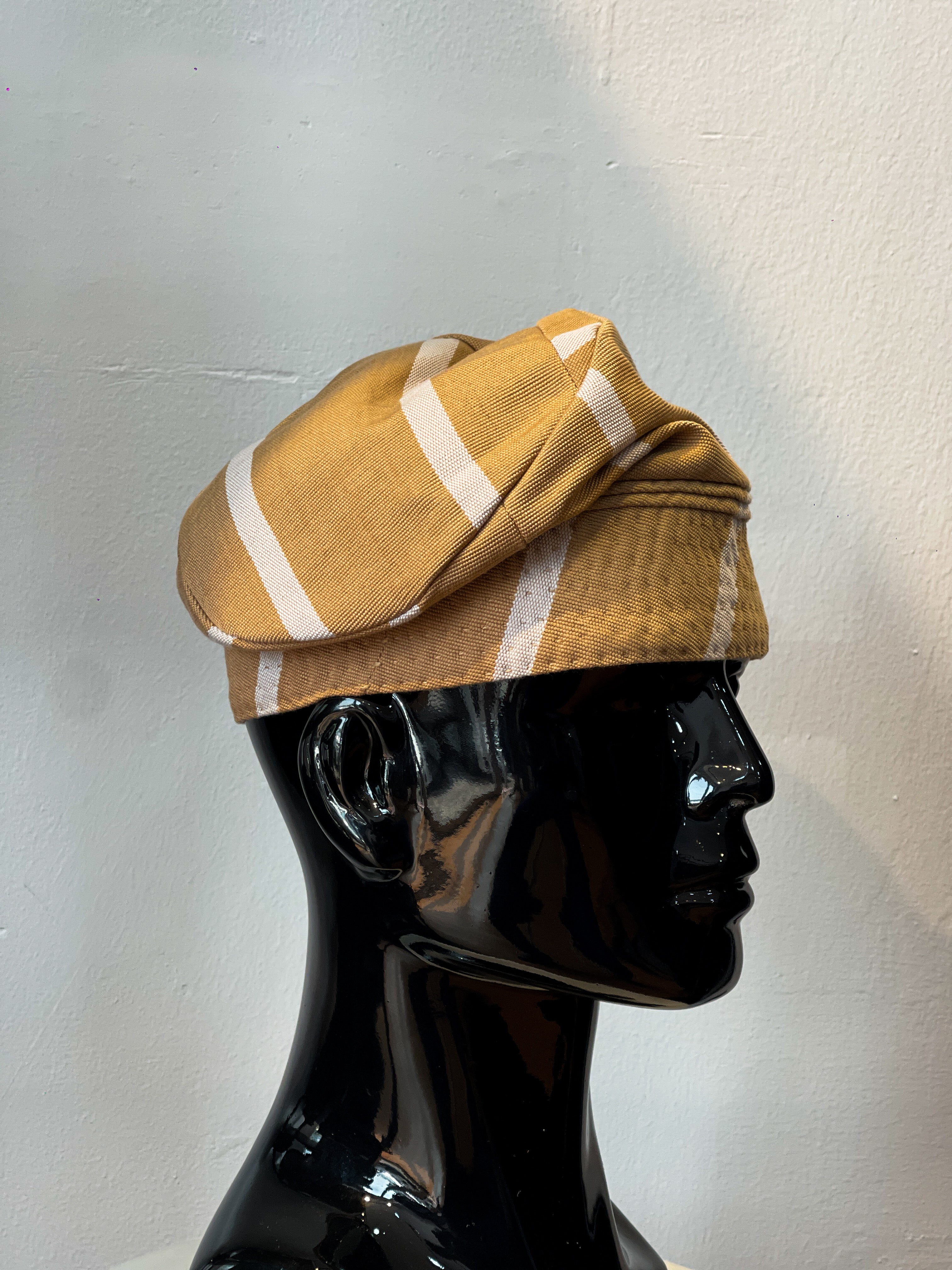 A traditional Nigerian Aso Oke cap displayed on a mannequin head, featuring a striped pattern in yellow and white colors.